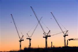 Four tower cranes set against a dusk sky on a construction site in Australia