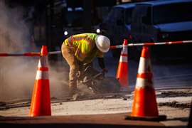 Worker cut concrete on the street during road works outside in USA city