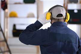 A construction worker adjusts hearing protection. (Image: Adobe Stock)