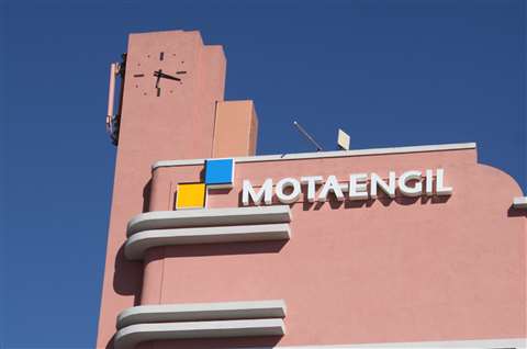 A pink building bearing Mota-Engil's logo against a blue sky